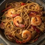 Black skillet filled with shrimp lo mein noodles and sesame seeds