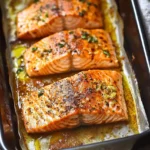Close-up of salmon fillets baked in a tray with garlic herb butter, lemon-free recipe